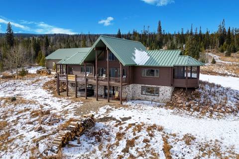 Exterior of large log cabin home with snow on the ground