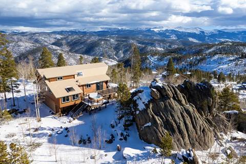 Home on a hill surrounded by the rocky mountains next to large boulders