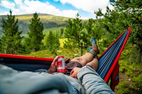 Man in hammock with can of beer in hand in the trees