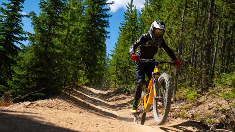 Child riding a downhill mountain bike on a trail at Trestle Bike Park in Colorado