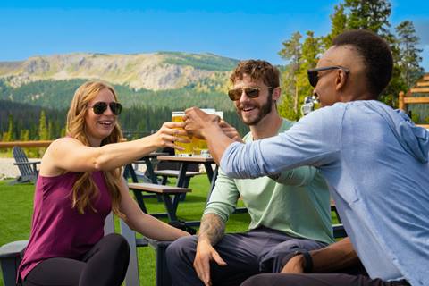 Group of 3 people cheersing beers in the mountains. 