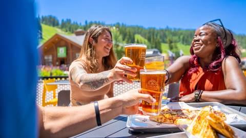 Group of people cheersing and eating food on a outside patio at Winter Park Resort.