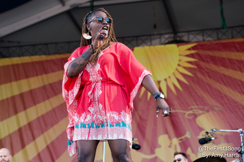 Woman singing on stage with microphone in her hand.