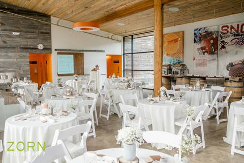 Wedding reception inside a modern space with multiple dining tables set with white linens at Winter Park Resort, Colorado