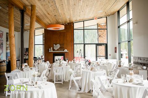 Wedding reception inside a modern space with multiple dining tables set with white linens at Winter Park Resort, Colorado