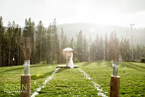 Colorado mountain wedding with bride and groom kissing under an umbrella in the rain at Winter Park Resort. 