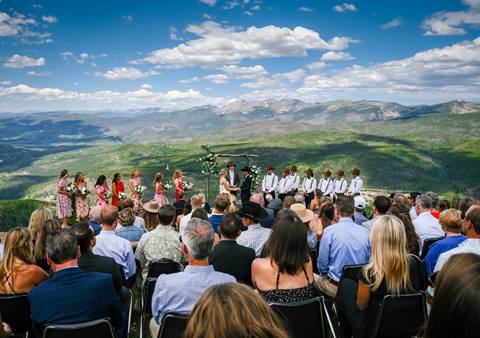 Summer mountaintop wedding at Winter Park Resort, bride and groom at altar with bridal parties and guests watching. 