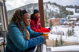 Two people on a balcony overlooking Winter Park Ski Resort Colorado