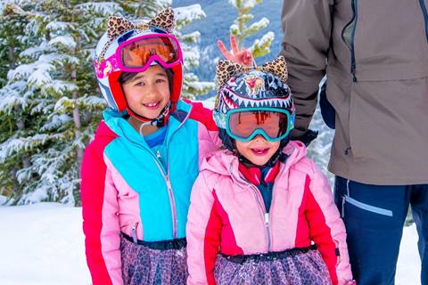 Two children in colorful ski clothing smiling at the camera at Winter Park Resort