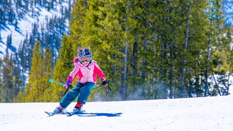 Child skiing in colorful outfit on groomed run at winter park resort