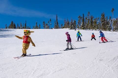 Children skiing behind Winter Park Resort mascot Parry the Dog. 