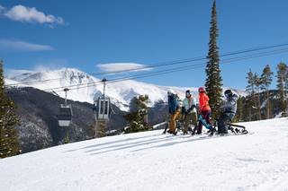 Group of 3 people ride SnoGo ski bikes at winter park